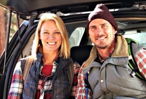 Couple Sitting on Car, Outdoors in Nature, Smiling, Wearing Vests and Hats