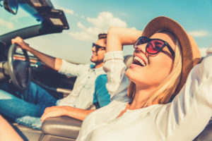 Woman and Man Driving in Car, Woman Has Hands Up, Summer Day, Smiling Faces