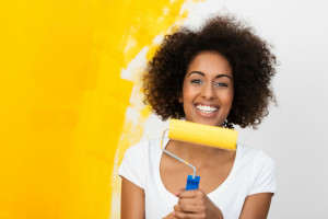 Woman Holding Paint Brush, Yellow Partially Painted Wall