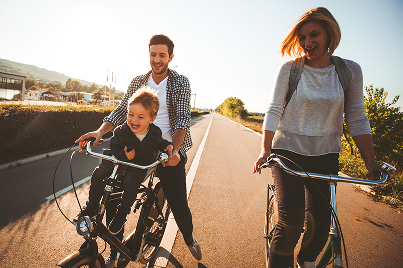 Mother, Father and Son Smiling While Riding Bikes on Street, Summer Season