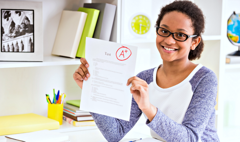 Student Holding a Graded Paper, Smiling, Home Setting