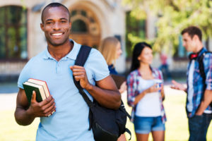Student Smiling With Books, College Settings, Students in Background Conversing
