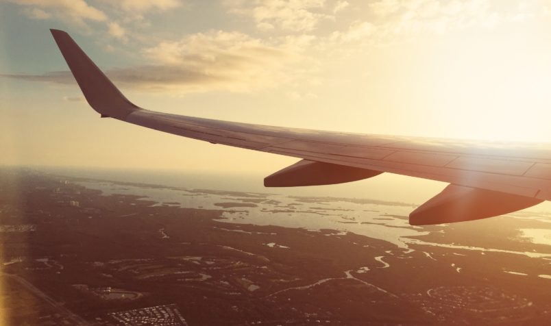 Airplane Wing, Flying In Air, Ocean, Land Below, Sunshine