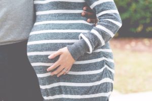 Pregnant woman and husband, woman touching stomach, nature background