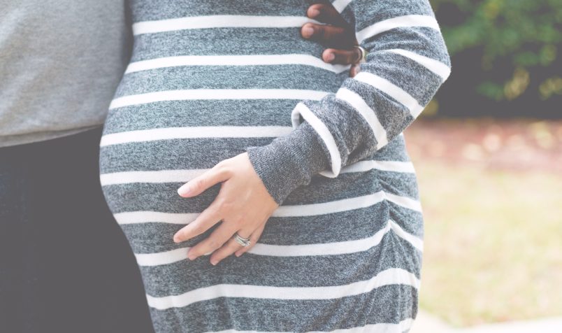 Pregnant woman and husband, woman touching stomach, nature background