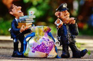 Figurines of Police Holding Hand Cuffs and Tax Man, Bag of Money, Street Background