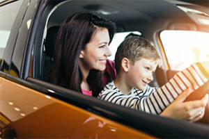 Mother and son choosing a new car to buy at the car showroom.