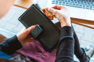 Woman sitting at a desk while pulling a credit card out of her black wallet
