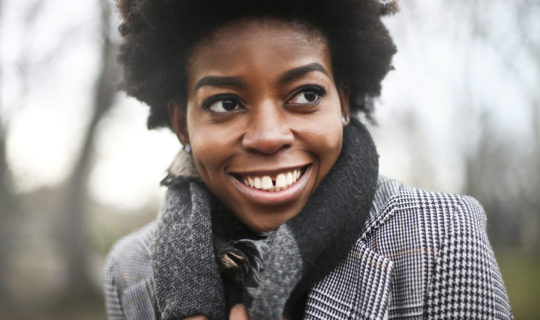 woman in forest clenching her coat