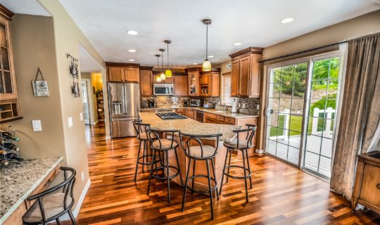 Newly updated contemporary classic open concept kitchen with new stainless steel appliances and granite counter top, a seating dining counter with bar stools, painted white kitchen cabinet and hardwood flooring. A model showcase interior design for residential kitchen.