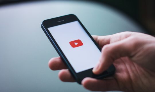 Hand holding iphone with YouTube logo