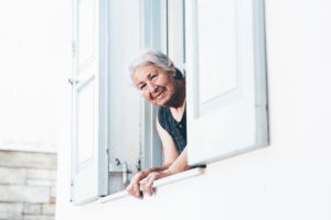Happy elderly woman with head out of the window of her house