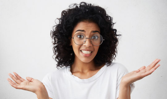 Confused millennial woman with hands up in the air