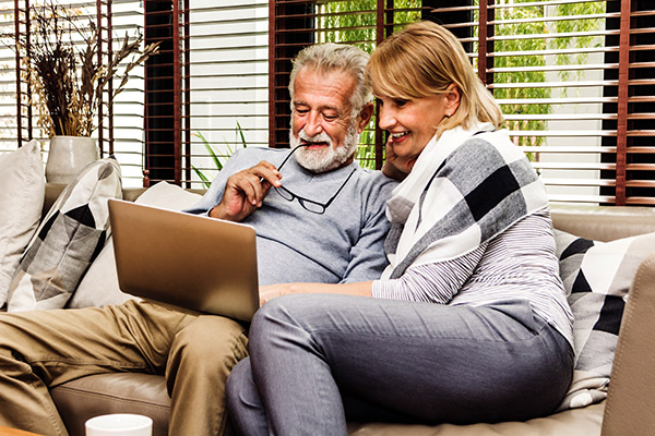 Two mature adults sitting on the sofa looking at their computer