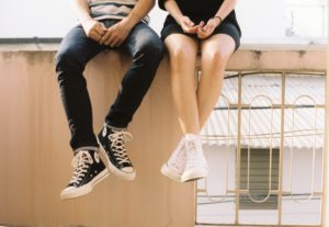 two teenagers sitting on a wall