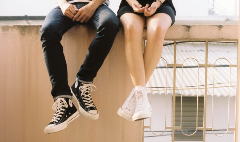 two teenagers sitting on a wall