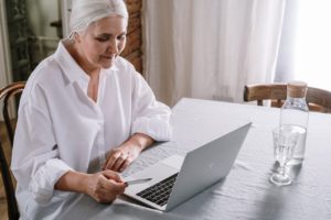 one lady looking at computer screen sitting at her kitchen table