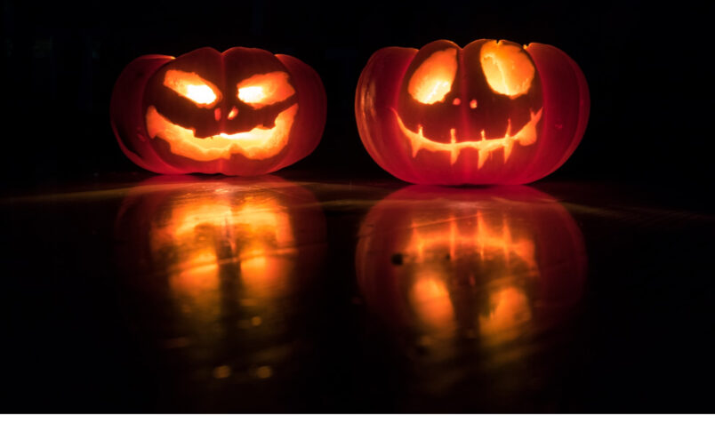 Two pumpkins, in the dark, carved, different faces, spooky, halloween